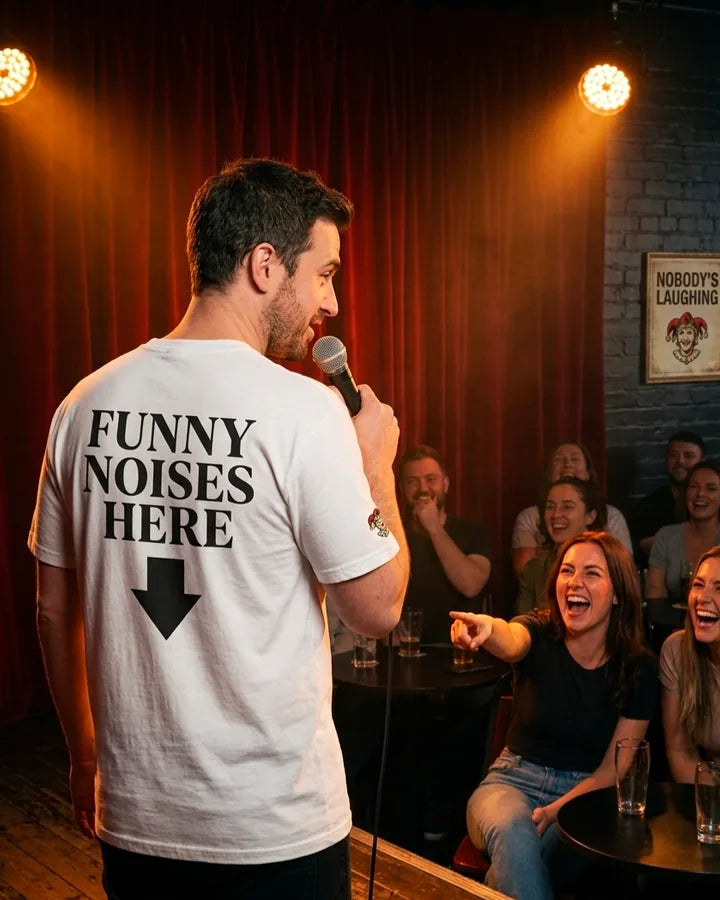 Funny Noises Here white comedy shirt worn on stage at a comedy show with audience laughing